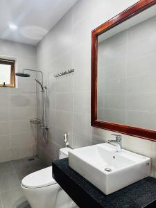 a bathroom with a sink and a toilet and a mirror at Nutty Village Phu Quoc in Phú Quốc
