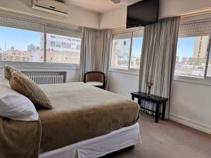 a bedroom with a bed with windows and a television at Hotel Corbel Superior by bund in Mar del Plata