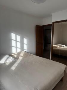 een slaapkamer met een wit bed en een spiegel bij La Maison Douce in Châtillon-sur-Seine