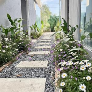 um caminho de jardim com flores na lateral de um prédio em T-Homestay Bình minh xanh  mais 14 fotografias