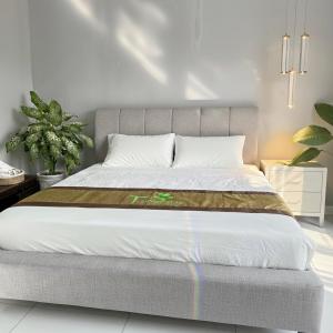um quarto com uma cama grande com lençóis brancos em T-Homestay Bình minh xanh 