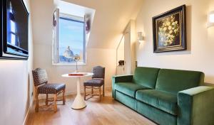 a living room with a green couch and a table at Hôtel Prince de Conti - Hôtel Rénové in Paris