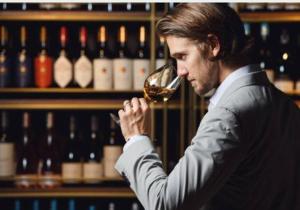 a man drinking a glass of wine in front of wine bottles at Chambres d'hôtes in Saint-Paul-Trois-Châteaux +16 photos
