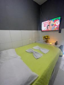 een kamer met een bed met groene lakens en een flatscreen-tv bij Hotel saffire in Feira de Santana