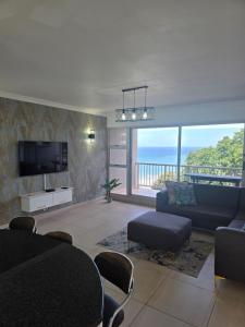 a living room with a couch and a television at 101 Camarque - 3 Bedroom Beachfront Apartment In Umdloti - 180 Degree Sea Views in Umdloti