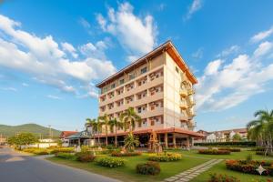 um grande edifício com palmeiras e uma rua em SCN Rayong โรงแรมเอส ซี เอน ระยอง em Ban Chang