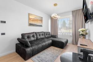 a living room with a leather couch and a television at Apartament 1 C4 Grand Chalet Poiana Brasov in Braşov