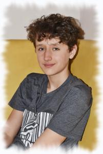 een jonge jongen met krullend haar zit op de grond bij Penzion Brzotín in Brzotín