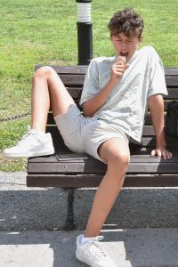 een jonge man zit op een bankje te eten bij Penzion Brzotín in Brzotín