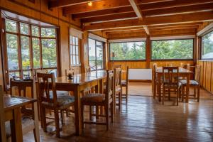 een eetkamer met tafels en stoelen en ramen bij Hotel Boutique 3 Pasos in Cerro Castillo