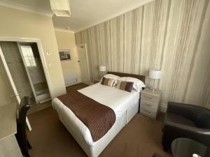 a hotel room with a bed and a chair at Alexander's in Hastings