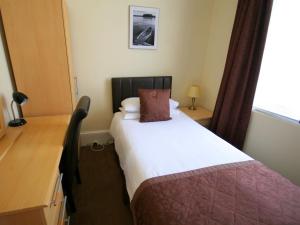a bedroom with a bed with a desk and a window at Alexander's in Hastings