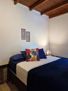 een slaapkamer met een bed met blauwe lakens en kussens bij Pousada das Palmeiras in Garopaba