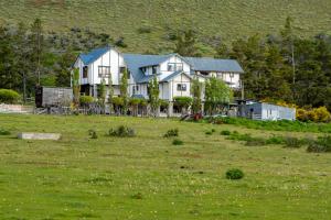 een groot wit huis in een grasveld bij Hotel Boutique 3 Pasos in Cerro Castillo