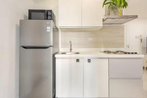 a white kitchen with a refrigerator and a sink at Sabrina'sCrib Apartment 2BR by Azure Residences Near Manila International Airport in Manila +61 photos
