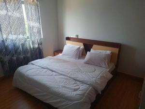 ein Bett mit weißen Laken und Kissen in einem Schlafzimmer in der Unterkunft Georgina's Court in Trofwi