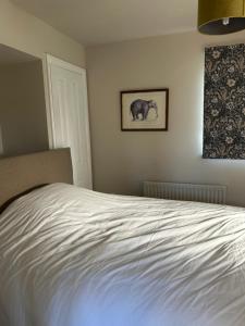 a white bed in a bedroom with a picture of an elephant at The Nest in Bourne