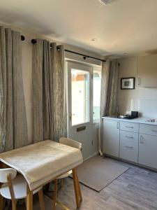 a room with a table and a kitchen with a window at The Nest in Bourne
