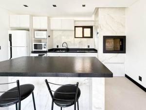 una cucina con bancone nero e 2 sedie di Vila do Sol a Florianópolis Altre 26 foto