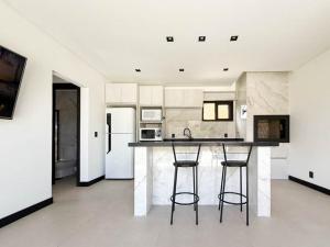 una cucina con bancone e 2 sgabelli da bar di Vila do Sol a Florianópolis