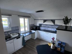 a kitchen with white cabinets and black counter tops at Apartment Spiez - Lake view - for 7 guests in Thun