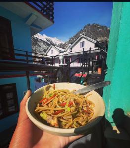 een persoon die een kom pasta vasthoudt met uitzicht bij Yamuna Guest House Tosh in Tosh