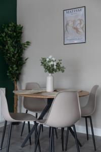 een tafel met stoelen en een vaas met bloemen erop bij Vacant Nests Ivy Cottage 3BR Wi-Fi in Banton