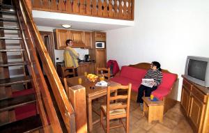 a man sitting on a red couch in a living room at Résidence Odalys Le Front de Neige in Les Carroz d'Araches