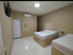 a room with two beds and a flat screen tv at Karajás Hotel in Quixeramobim