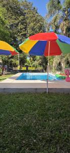 un ombrellone colorato nell'erba accanto a una piscina di Nuestra Casa en Paso a Paso de la Patria Altre 30 foto
