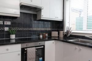 een keuken met witte kasten en een spoelbak bij Vacant Nests Ivy Cottage 3BR Wi-Fi in Banton +26 foto's