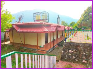 una piccola casa con tetto rosso e recinzione di Hotel Saanidhya Blue Moon Palace Inn Near Bhimtal Lake- Wifi - Room Service - Parking Facilities - Velly view Hotel a Nainital