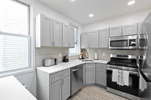 a kitchen with stainless steel appliances and white cabinets at The Harper Loft near Manhattan with NYC skyline view in Hoboken
