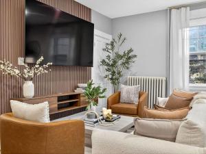 a living room with a couch and chairs and a tv at The Harvard Loft with Game Room and Free Parking Near Harvard Square in Cambridge