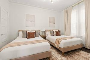 two beds in a bedroom with white walls at The Caleb Loft near Manhattan with NYC skyline view in Hoboken