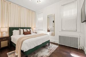 a white bedroom with a large bed and a mirror at The Caleb Loft near Manhattan with NYC skyline view in Hoboken