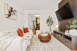 a living room with a white couch and a tv at The Caleb Loft near Manhattan with NYC skyline view in Hoboken +86 photos
