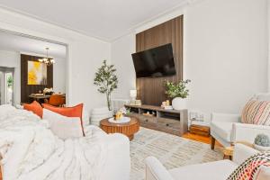 a living room with white furniture and a flat screen tv at The Caleb Loft near Manhattan with NYC skyline view in Hoboken