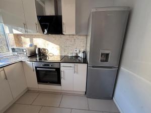 a kitchen with a stainless steel refrigerator and white cabinets at Canal Side Retreat in Maldon