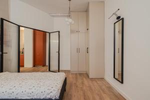 een slaapkamer met witte muren en een bed en spiegels bij Złota 7 Apartment in Warschau +28 foto's