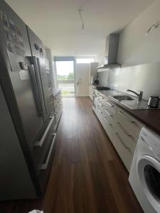 a kitchen with a stainless steel refrigerator and wooden floors at Chambre meublée avec dressing dans un grand appartement tout équipé au pied du tram cher habitant in Lormont