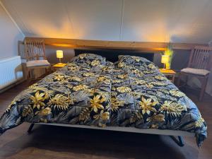 een bed met een blauw en geel dekbed en twee stoelen bij Beachloft Zeeland 1 in Scharendijke