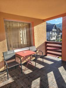 eine Terrasse mit einem roten Tisch und Stühlen auf dem Balkon in der Unterkunft LaBrazi in Şimon