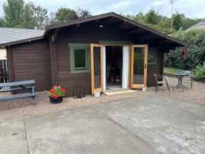 een klein huis met een tafel en een patio bij Glenhill Lodge in Roybridge