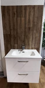 een witte wastafel in een badkamer met een houten muur bij Apartment Pottery - Park view in Thun +20 foto's