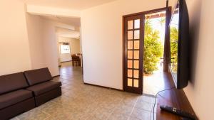 een woonkamer met een bank en een televisie bij Casa com Jacuzzi, Piscina e Garagem em Jacuipe in Barra de Jacuípe