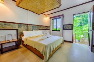 a bedroom with a bed and a large window at El Nido Viewdeck Cottages in El Nido