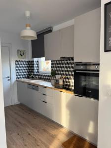 een keuken met witte kasten en zwarte apparaten bij Résidence de l'Authie in Groffliers