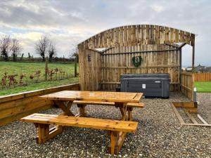een houten picknicktafel en bank voor een houten gebouw bij Kingarrow Cottage in Omagh