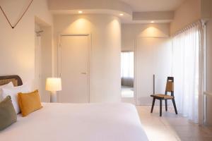 una camera da letto bianca con un letto e una sedia di Crisol Promenade a Nizza